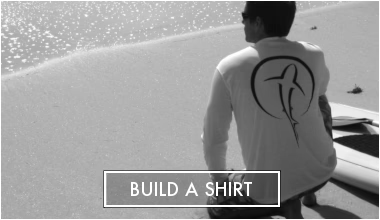 Build a shirt button with photo of Person wearing a white shirt with a Shark Zen black logo, keeling on a beach by a paddleboard.